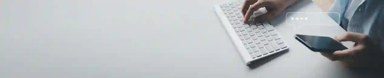Person using phone and typing on laptop